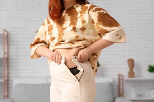 Image of woman trying to do her trousers up after pregnancy weight gain Bury St Edmunds